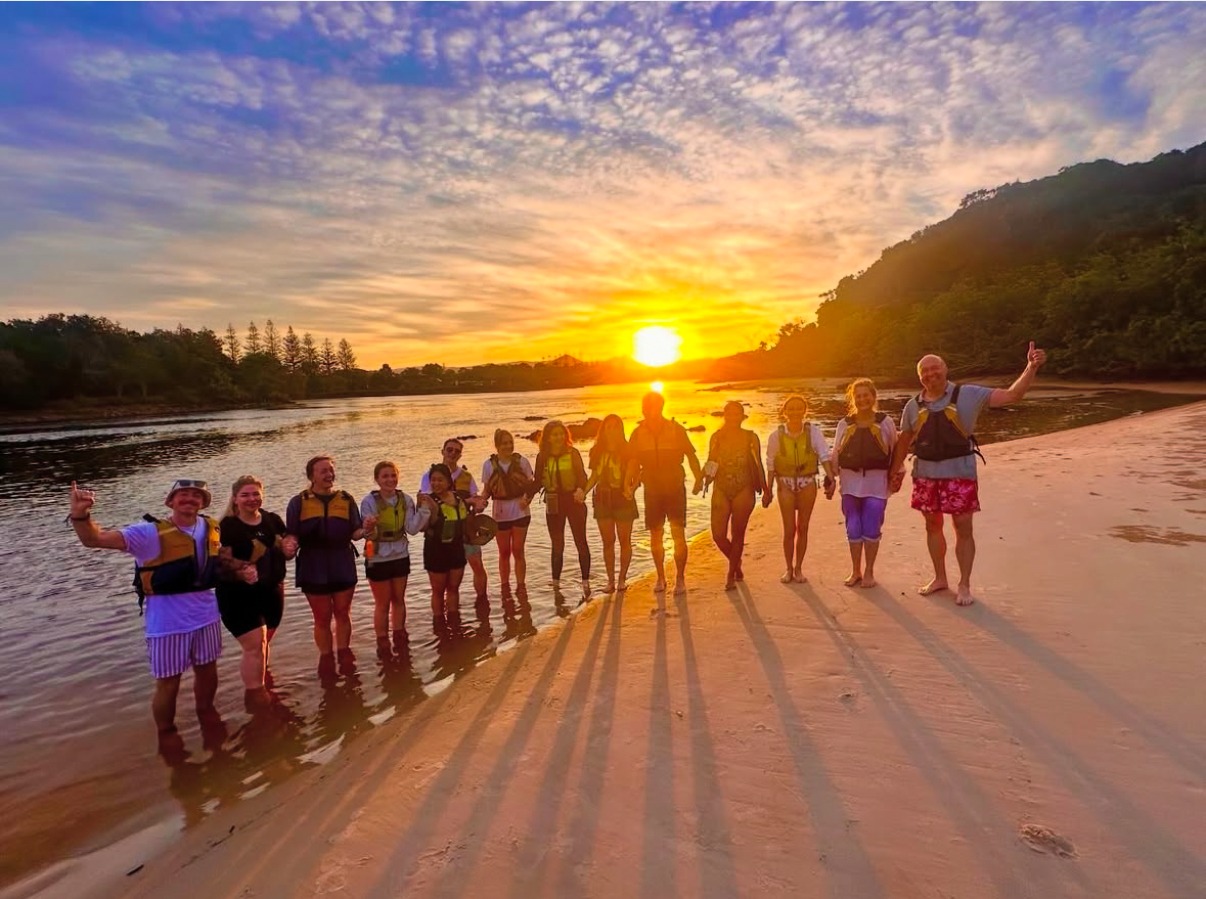 Go Sea Kayak guests together by the water at sunset